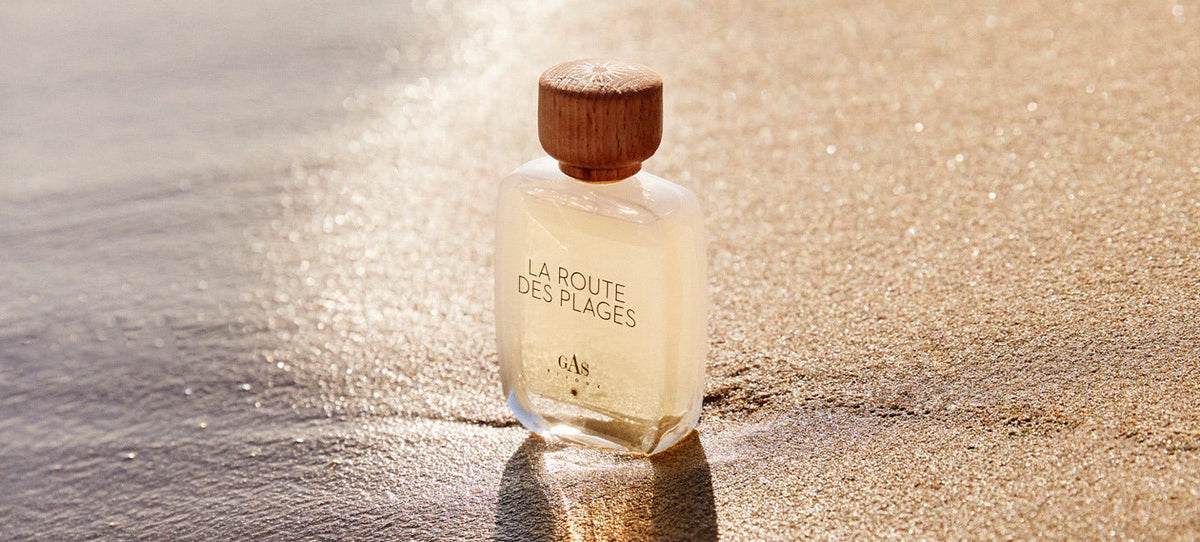 Gas Bijoux perfume bottle resting on sand in warm afternoon light