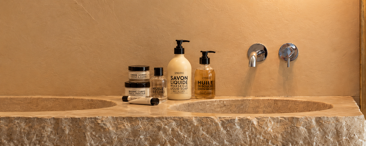 Compagnie de Provence body care bottles displayed on a wooden shelf